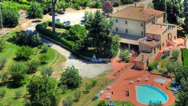 Vista aérea de uma propriedade com piscina, área de estar externa e um edifício grande com telhado de telhas.