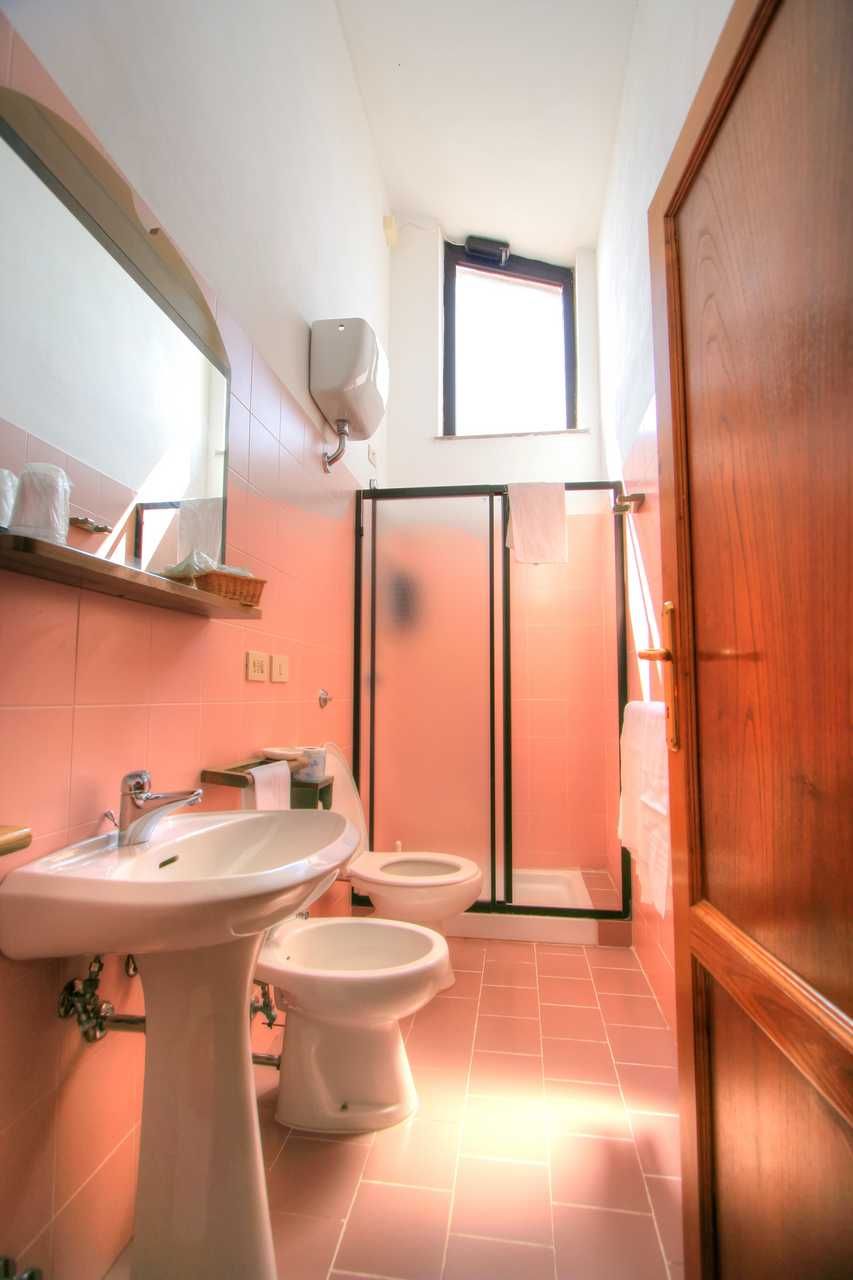 A bathroom with a sink, two toilets, a shower, and a wooden door.