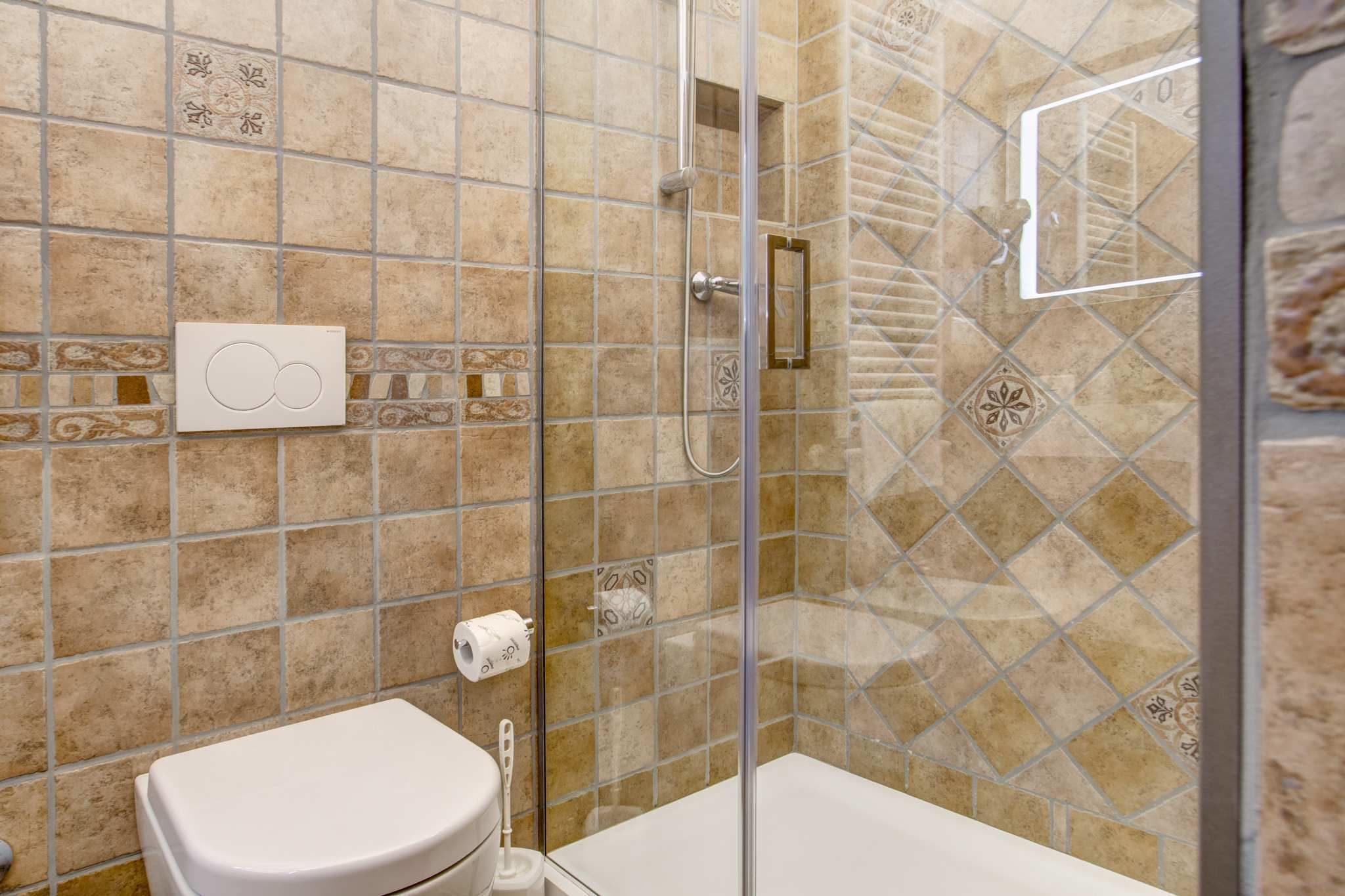 A bathroom with a glass shower enclosure, a toilet, and a towel rack.
