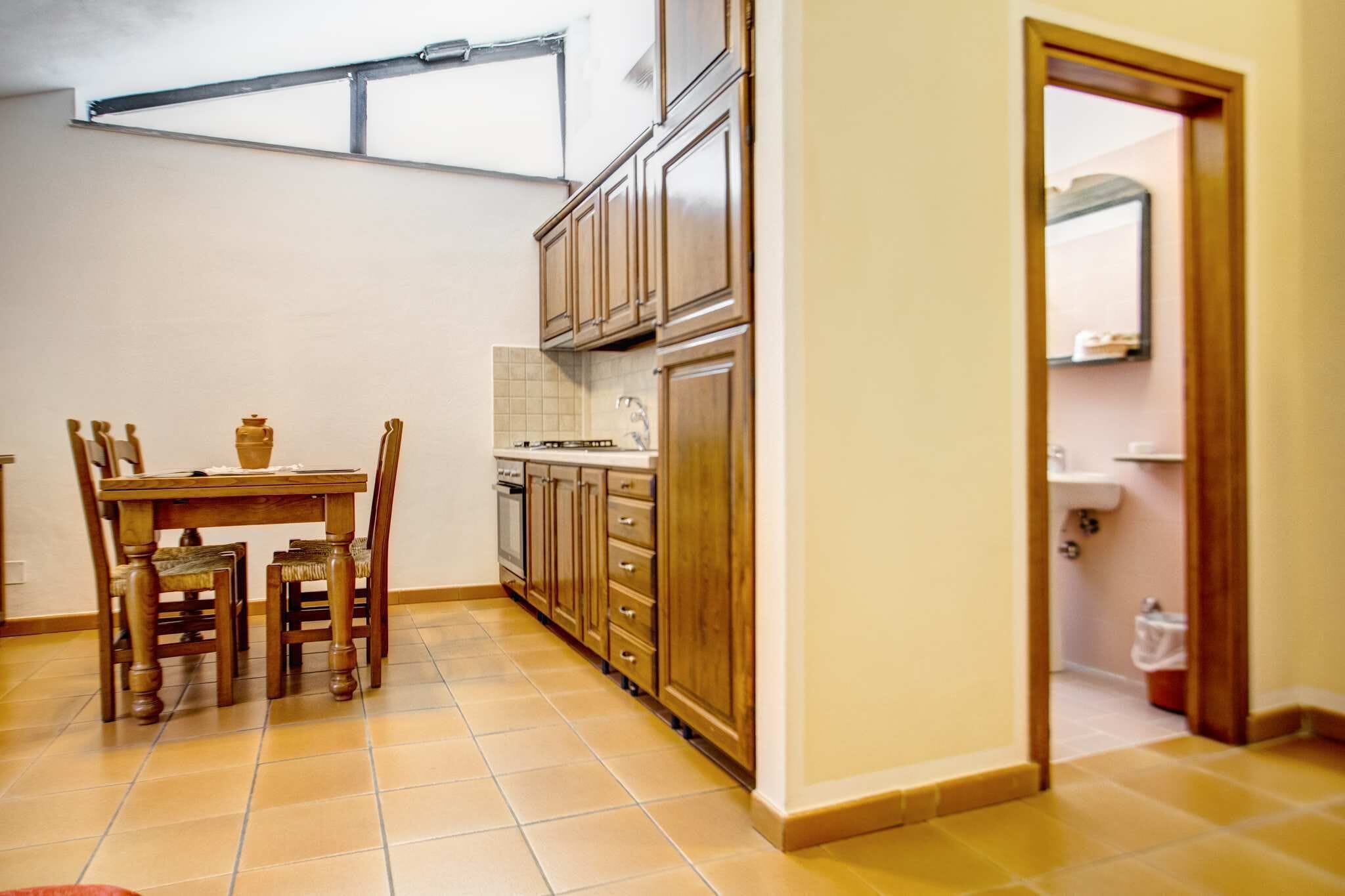 A kitchen with wooden cabinets, a dining table with chairs, and a window above the counter.