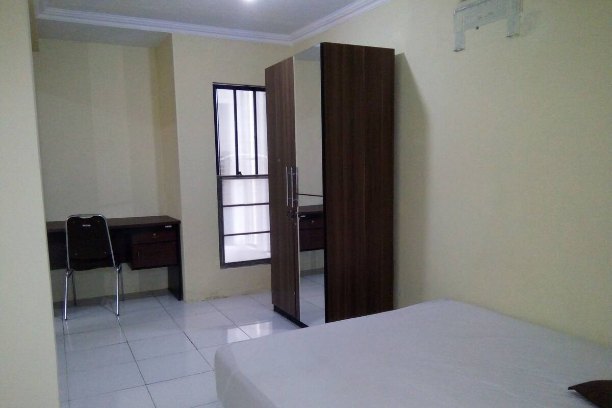 A bedroom with a bed, a desk, and a wardrobe.