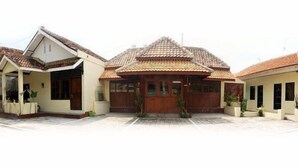 A building with a tiled roof, a central entrance with a wooden door, and two side wings with windows. - Ekost Danurejan (Yogyakarta)