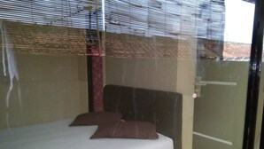 A bedroom with a bed, pillows, and a window with blinds. - Ekost Danurejan (Yogyakarta)