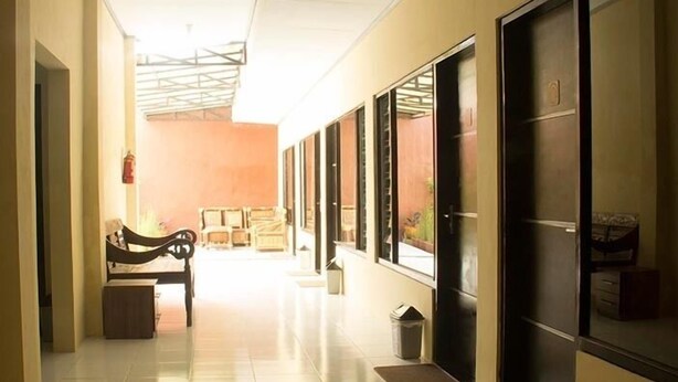 A hallway with a bench, a trash bin, and a door with a window. - Ekost Danurejan (Yogyakarta)