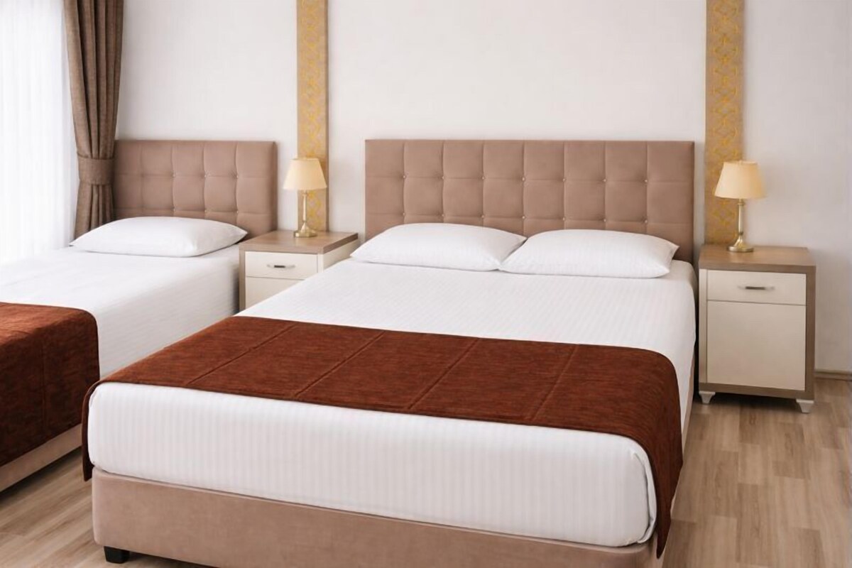 Et hotelværelse med to senge, hver med sengegavl, natborde og lamper.