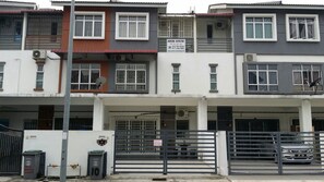 A multi-story residential building with balconies, a gated entrance, and a parked car.