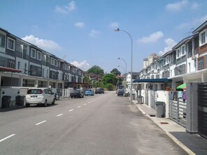 A residential street with multi-story houses, parked cars, and a clear sky.