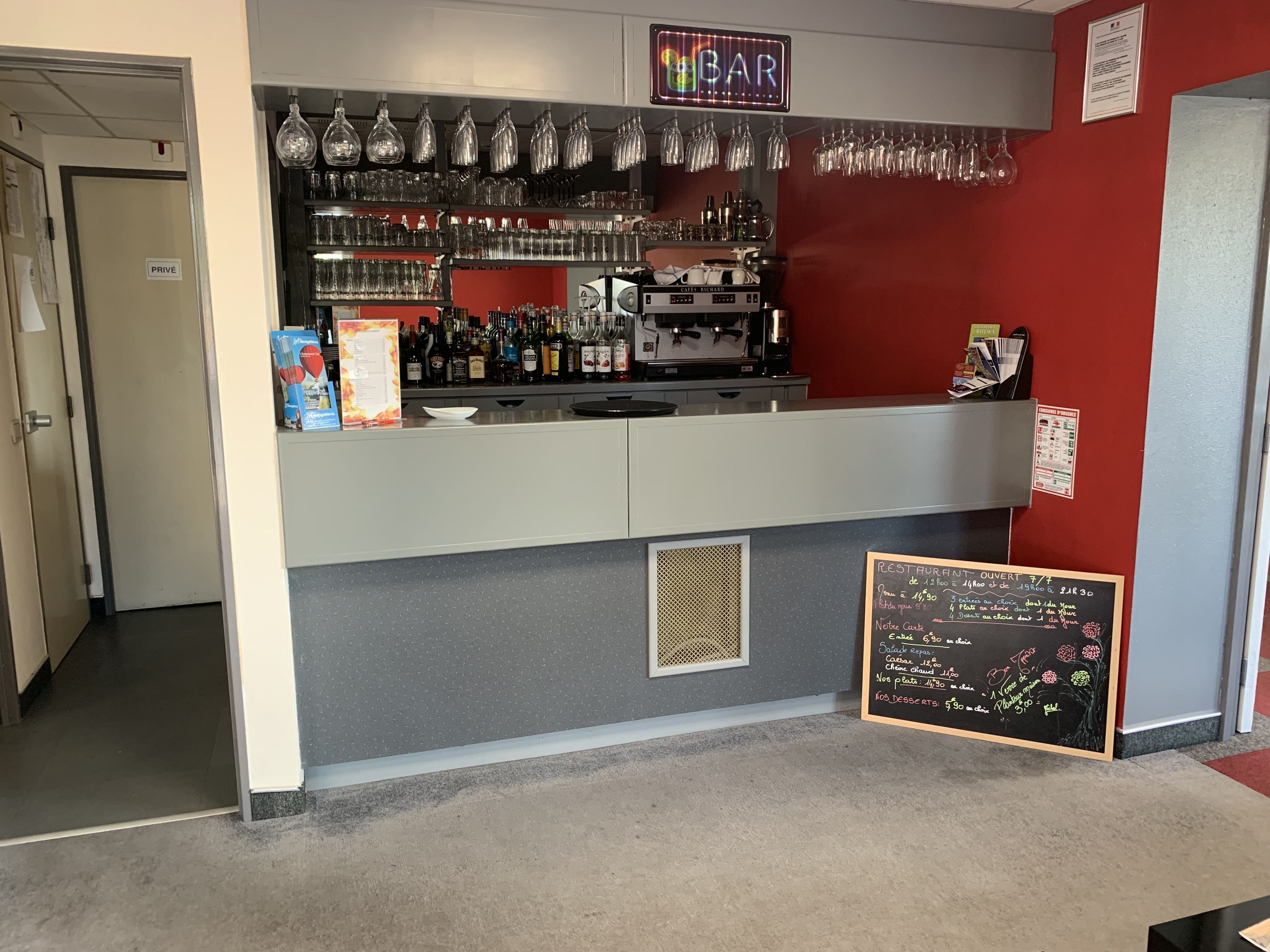 A bar area with a chalkboard menu, shelves of liquor bottles, and hanging glasses.