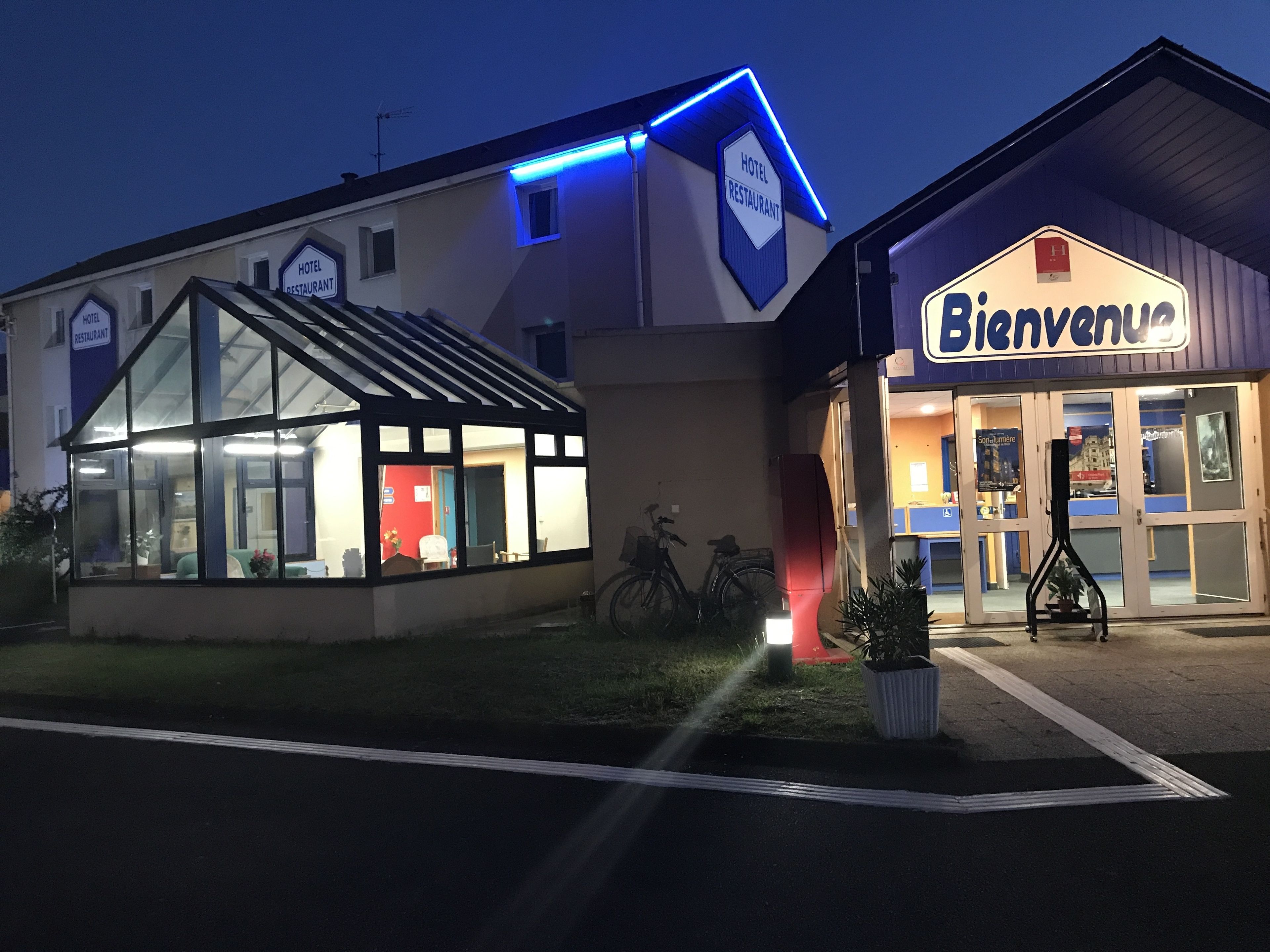 A hotel with a glass facade and a sign indicating it is a hotel and restaurant.