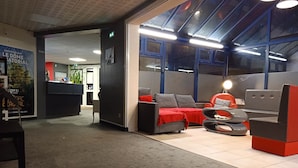 Un moderno vestíbulo de hotel con mostrador de recepción, zona de estar con sofás y sillones, y ventanas amplias que dejan entrar luz natural.