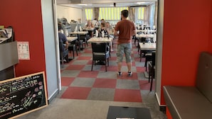 Un restaurante con paredes rojas, suelo de cuadros y mesas preparadas para comer.