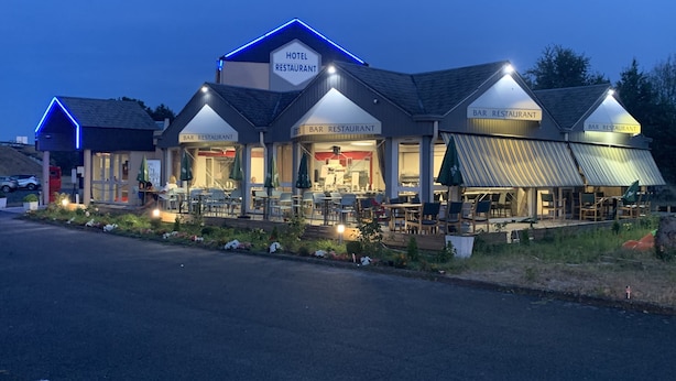 Un hotel con varios bares y restaurantes, terraza exterior e iluminación destacada en la fachada.