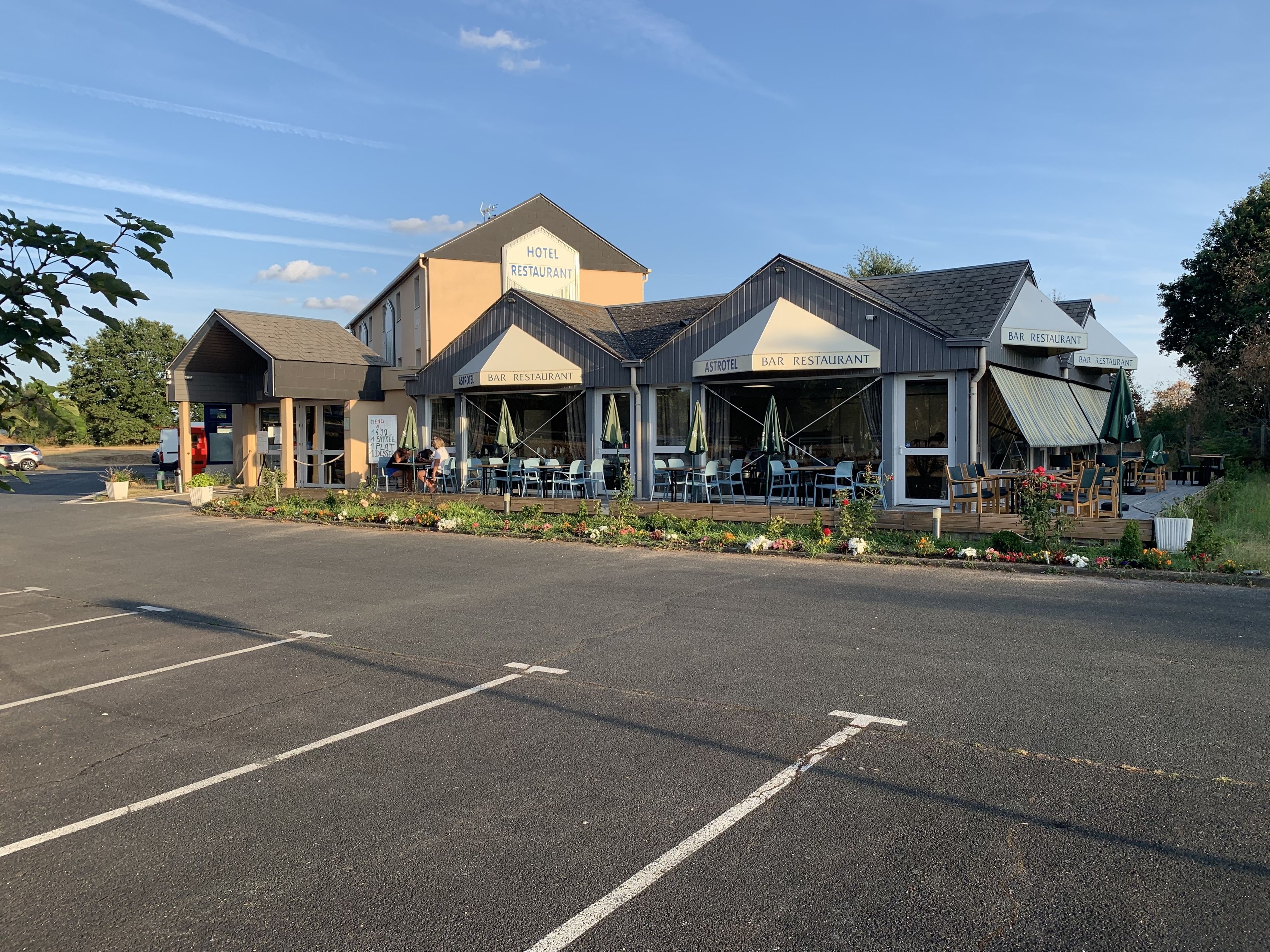 Un hotel con restaurante y bar, mesas al aire libre y aparcamiento.