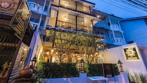 Un hotel de varios pisos con balcones, una entrada bien iluminada y un letrero que indica un restaurante en la planta baja.