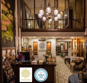 Un hall d’hôtel spacieux, doté d’un haut plafond, d’un lustre et d’un comptoir d’accueil.