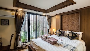 Habitación de hotel con una cama grande, una mesita de noche, una lámpara, una ventana con cortinas y un aire acondicionado instalado en la pared.