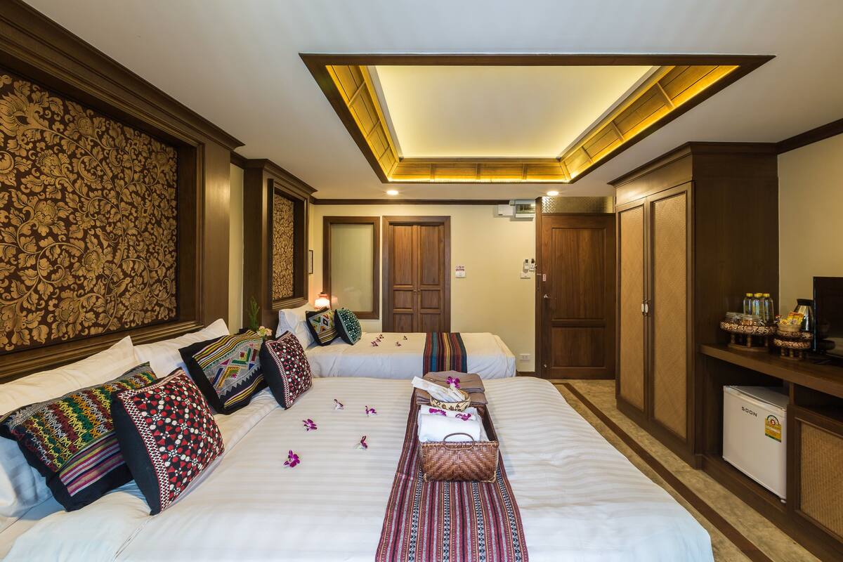 Una habitación de hotel con dos camas, un minibar y una lámpara en el techo.