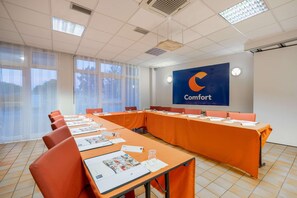 A conference room with a long table, orange chairs, and a large screen displaying the word "Comfort". - Comfort Hotel Montlucon (Montlucon)