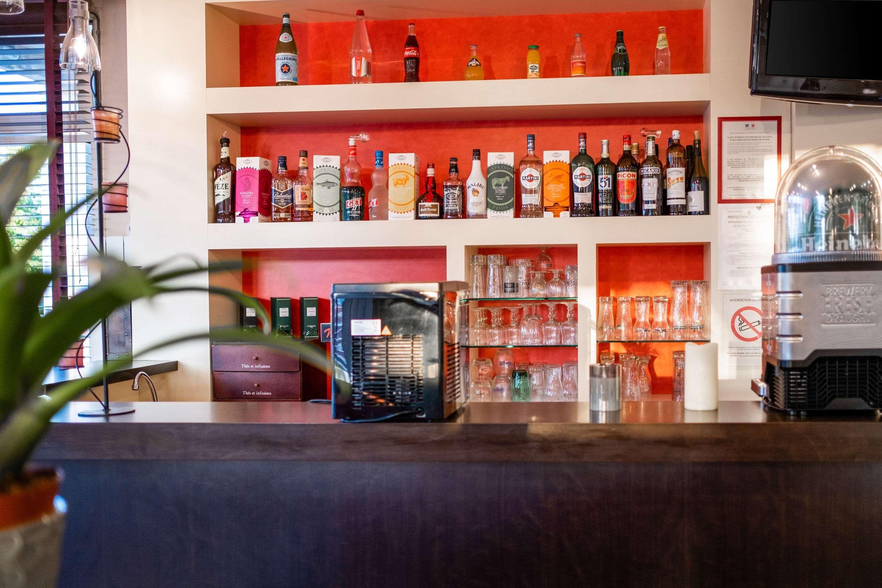 Zona de bar con estantes llenos de botellas de licor, vasos y un grifo de cerveza.