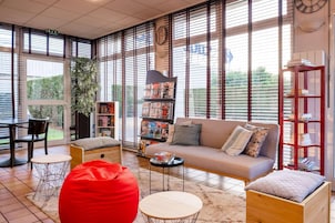 Una sala de estar moderna con sofá, sillón de peluche rojo y estantería.