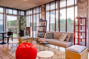 A modern living room with a sofa, red bean bag, and a bookshelf. - Comfort Hotel Montlucon (Montlucon)