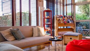 Un salon moderne avec un canapé, une bibliothèque rouge et une petite table d’appoint en bois.