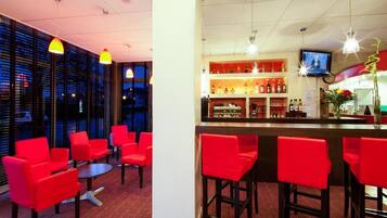 A bar area with red chairs and a counter.