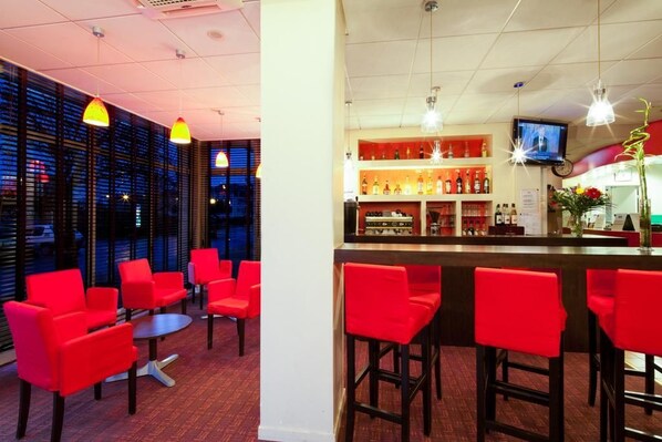 Een bar met rode stoelen en een toonbank.