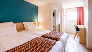 Une chambre d’hôtel avec deux lits, un bureau et une chaise.