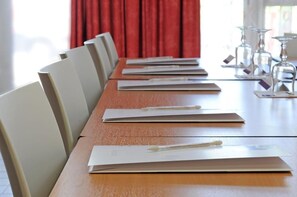 Una mesa de conferencias con sillas, documentos y bolígrafos.