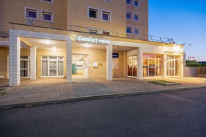 A Comfort Hotel with a tiled facade, a covered entrance, and a visible reception area. - Comfort Hotel Montlucon (Montlucon)
