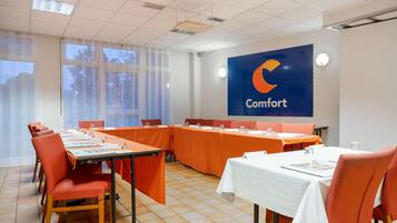 A conference room with a long table, orange chairs, and a large blue banner with the word "Comfort" on the wall.