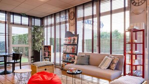 Un salon moderne avec un canapé, un fauteuil en forme de sac de haricots rouge et une bibliothèque.