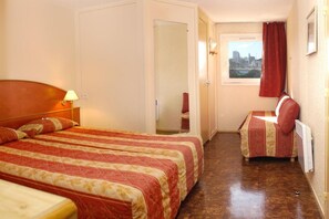 Een hotelkamer met twee bedden, een klein bureau, een raam met uitzicht en een deur naar een andere kamer.
