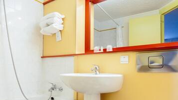 Un baño con lavamanos blanco, un espejo y un perchero para toallas.