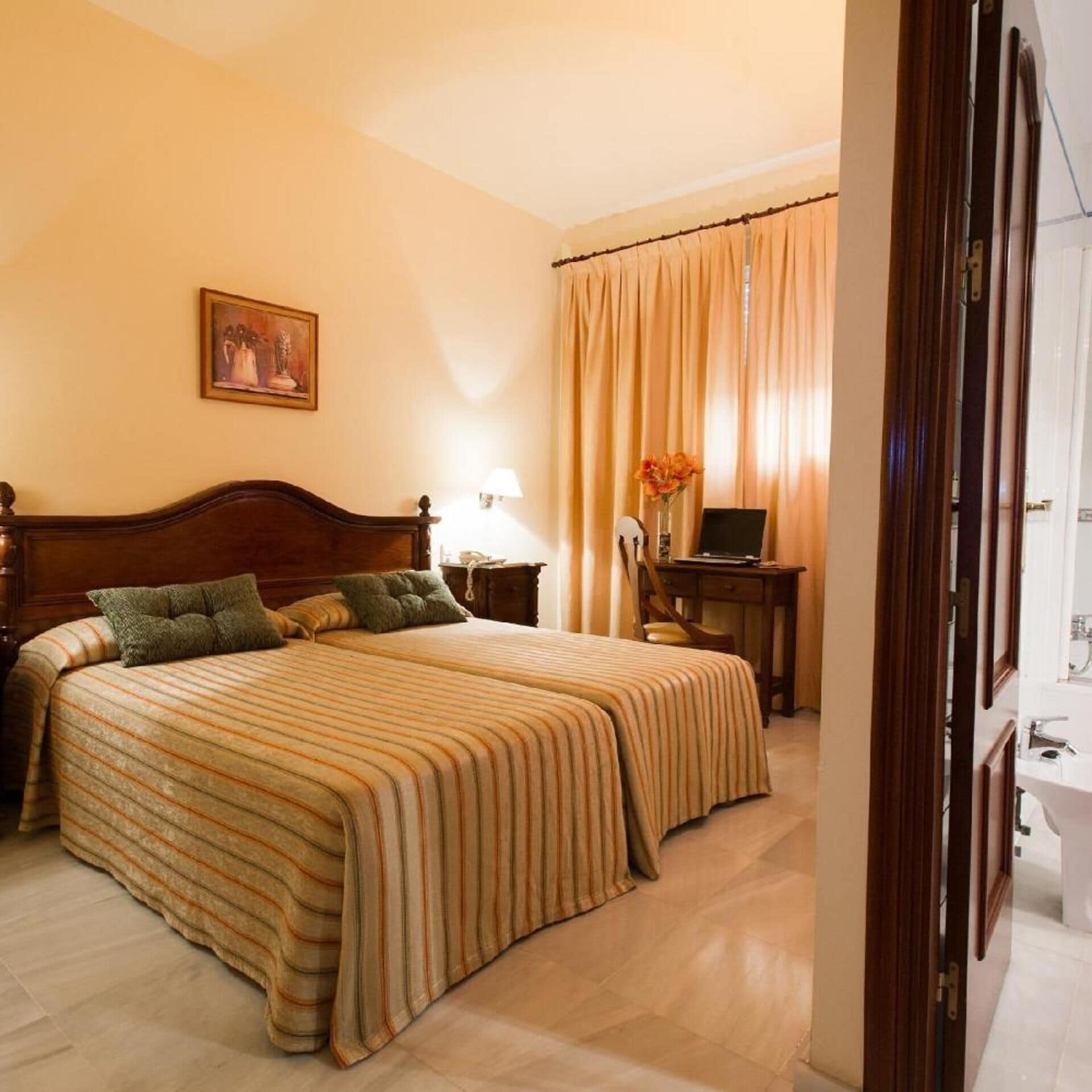 A hotel room with a large bed, a desk, a chair, a lamp, and a painting on the wall.