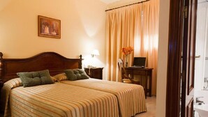 A hotel room with a large bed, a desk, a chair, a lamp, and a painting on the wall.