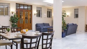 A dining area with a table set for two, a sofa, and a wooden bench.