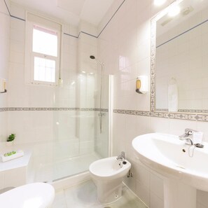 A bathroom with a glass-enclosed shower, a bidet, a sink, and a mirror. - Hotel Leflet Gran Avenida (Coria del Rio)