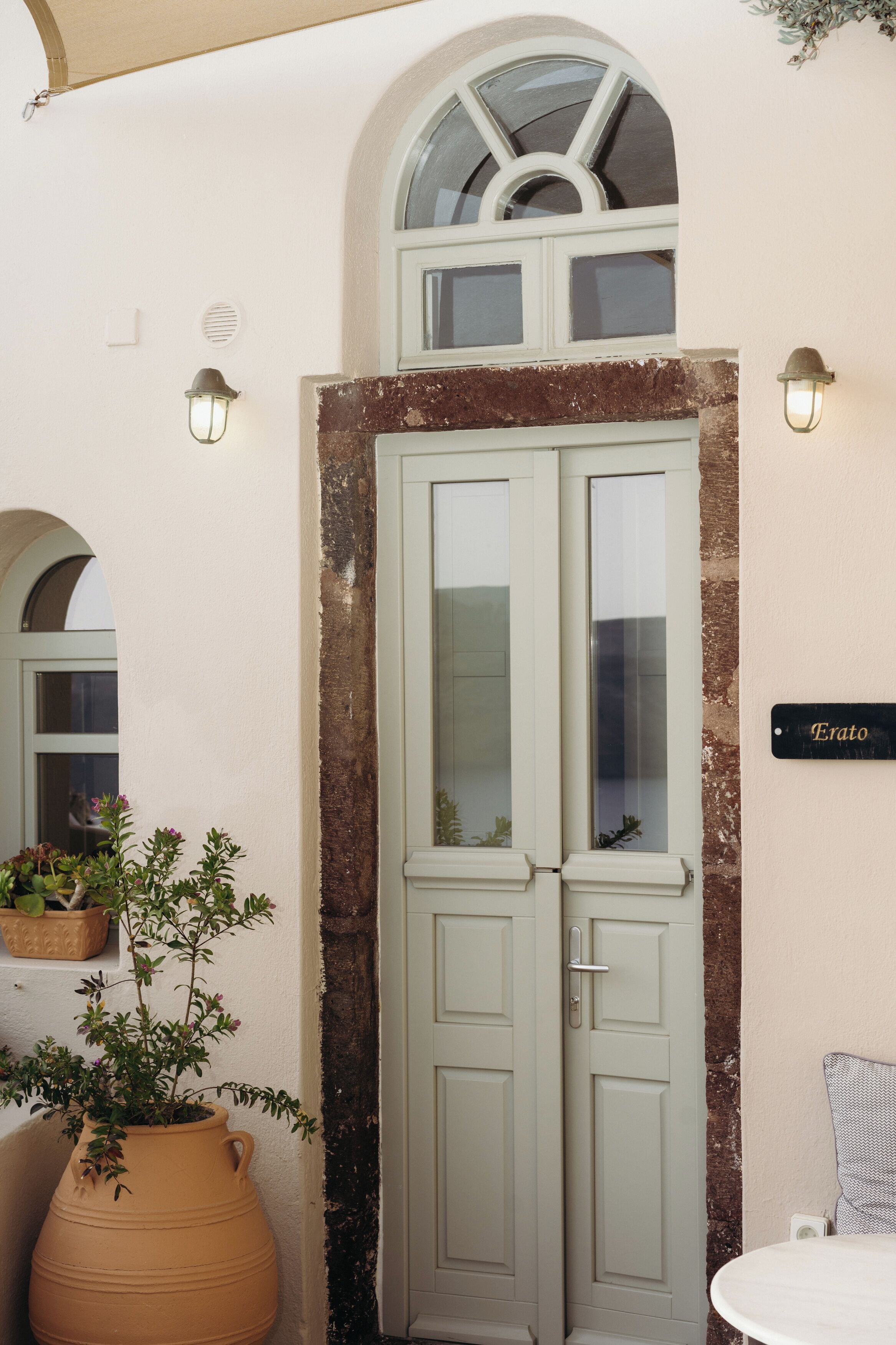 A door with a nameplate, a potted plant, and a small table.