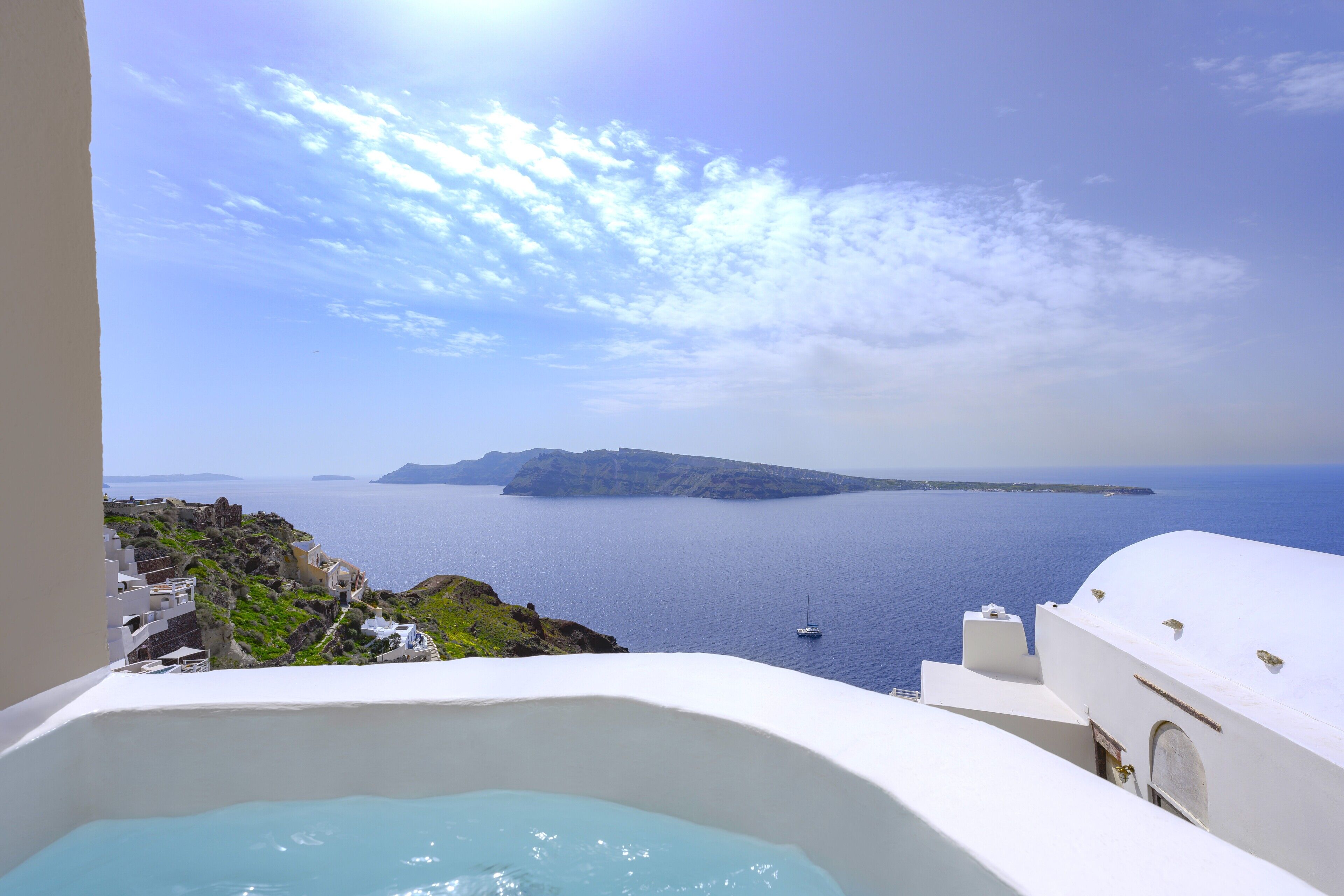 A view of a white building with a large bathtub, a clear blue sky, and the sea in the background.