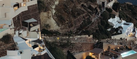 A coastal town with white buildings, a rocky hillside, and a view of the sea.