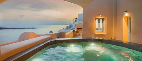A hot tub with a view of the sea, a lounge area, and a window with a view.