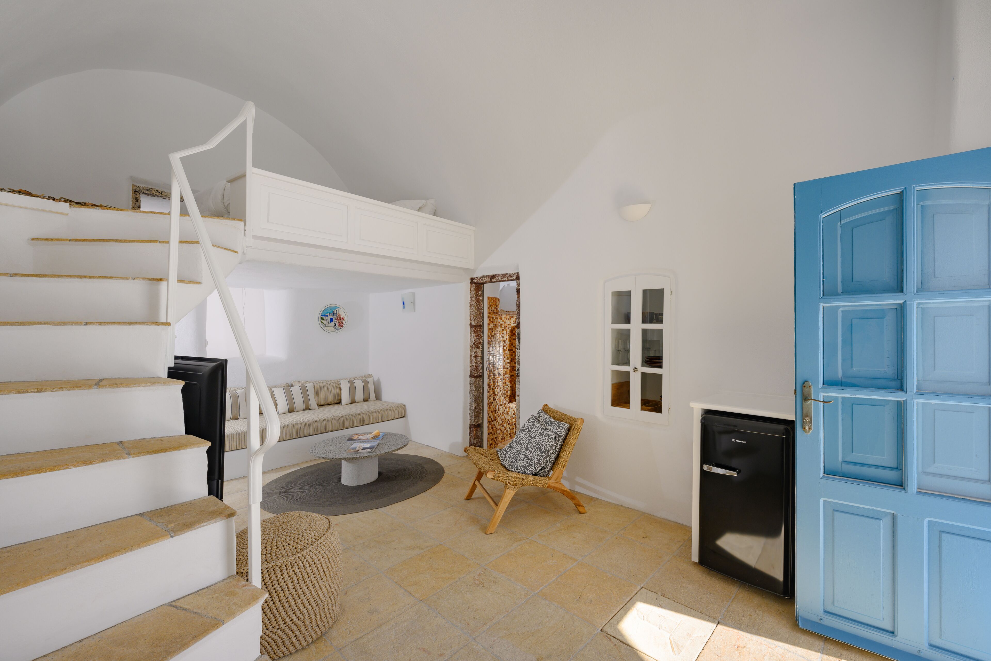 A modern interior with a staircase, a sofa, a small table, and a blue door.