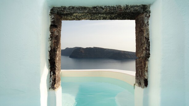 A bathtub with a view of a body of water and a distant landmass.