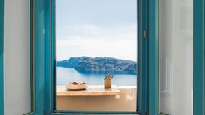 A room with a view of a mountainous coastline through a window.