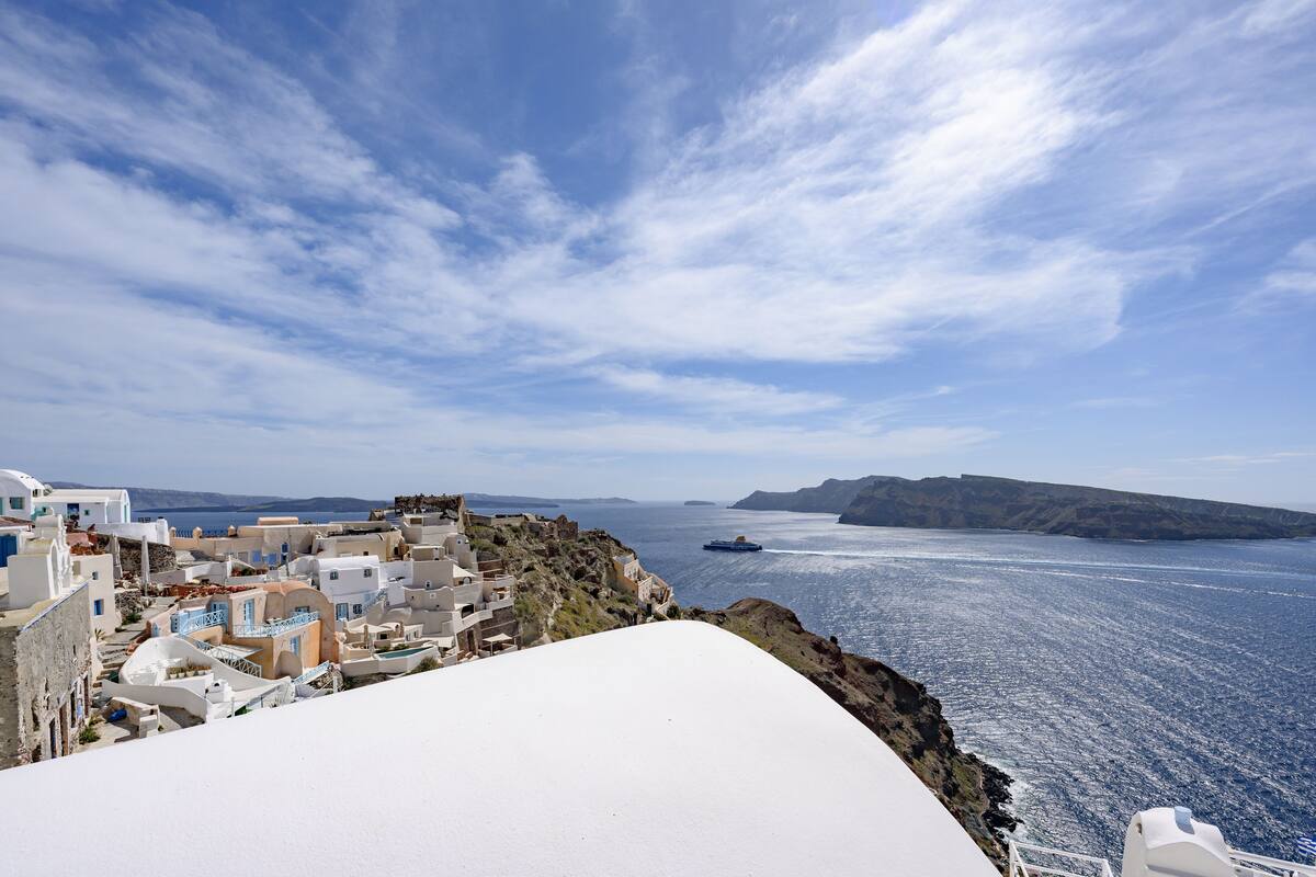 Un pueblo costero con edificios blancos, un cielo azul despejado y el mar.