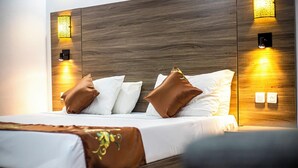 Une chambre d’hôtel moderne avec une tête de lit en bois, du linge de lit blanc et des coussins décoratifs.