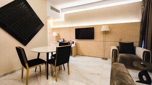 Une chambre d’hôtel moderne dotée d’un coin repas, d’un canapé et d’une télévision à écran plat.