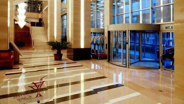 Eine geräumige Lobby mit hoher Decke, großen Fenstern und einer zentralen Treppe.